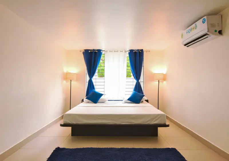 A first-floor bedroom, bed centred between the windows